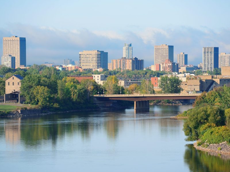 Ottawa cityscape in the day over river with historical architecture.